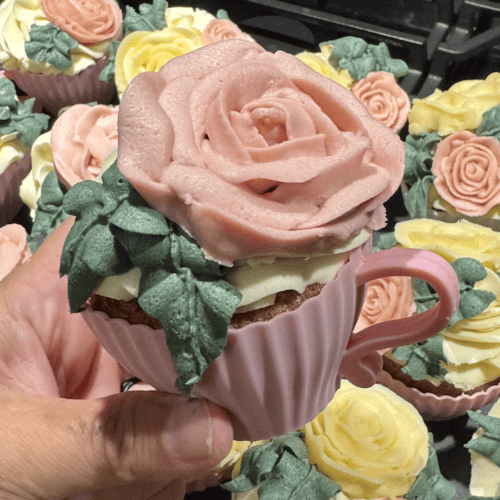 A sea of beautifully piped buttercream rose petal flowers and designs on vanilla cupcakes that are baked into silicone pink tea cups.