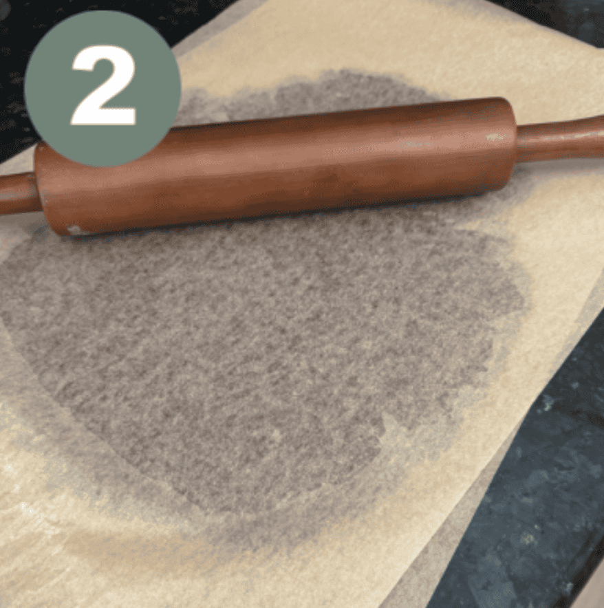 Brown Rolling pin on top of on a piece of brown parchment paper with a brown circle underneath with a green circle with a white number 2 in the upper lefthand corner 