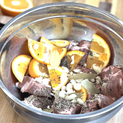 Fresh orange slices and raw meat in a glass bowl for marinade.