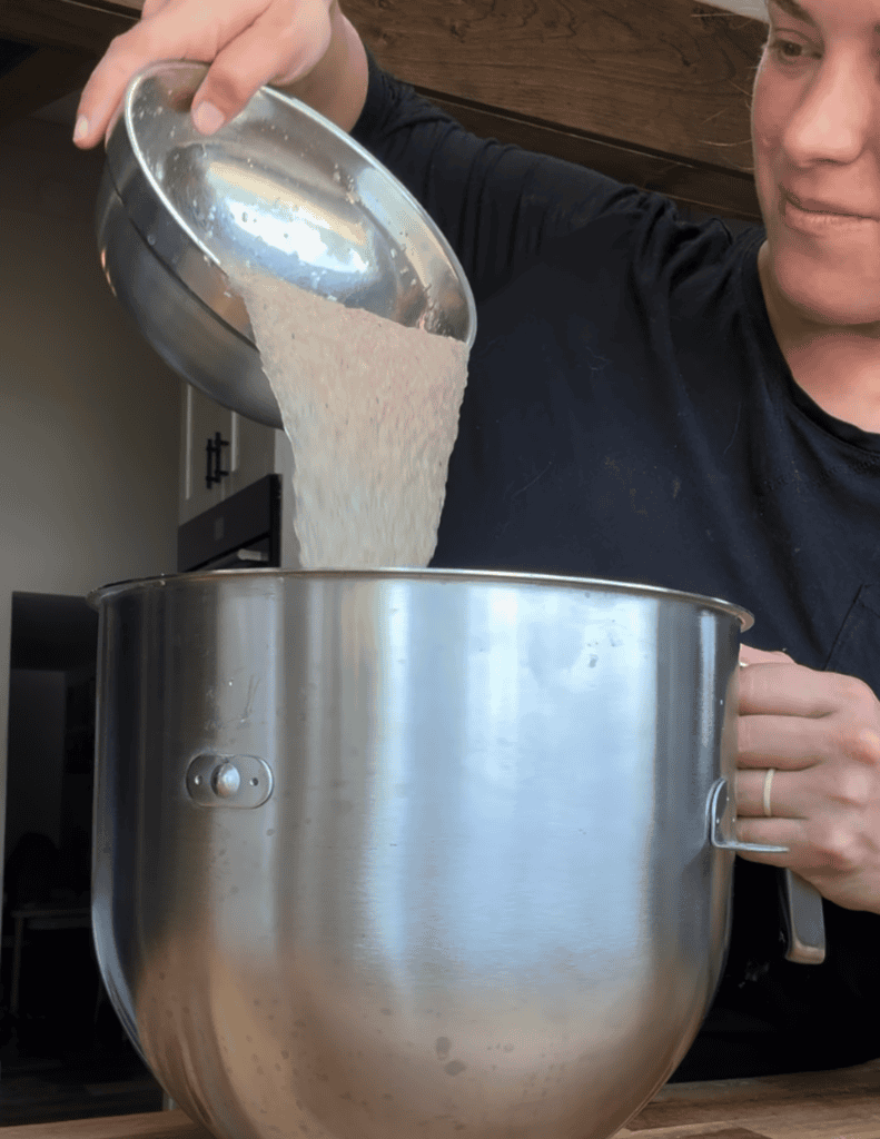 Person pouring gluten-free flour into a mixing bowl for pizza dough.