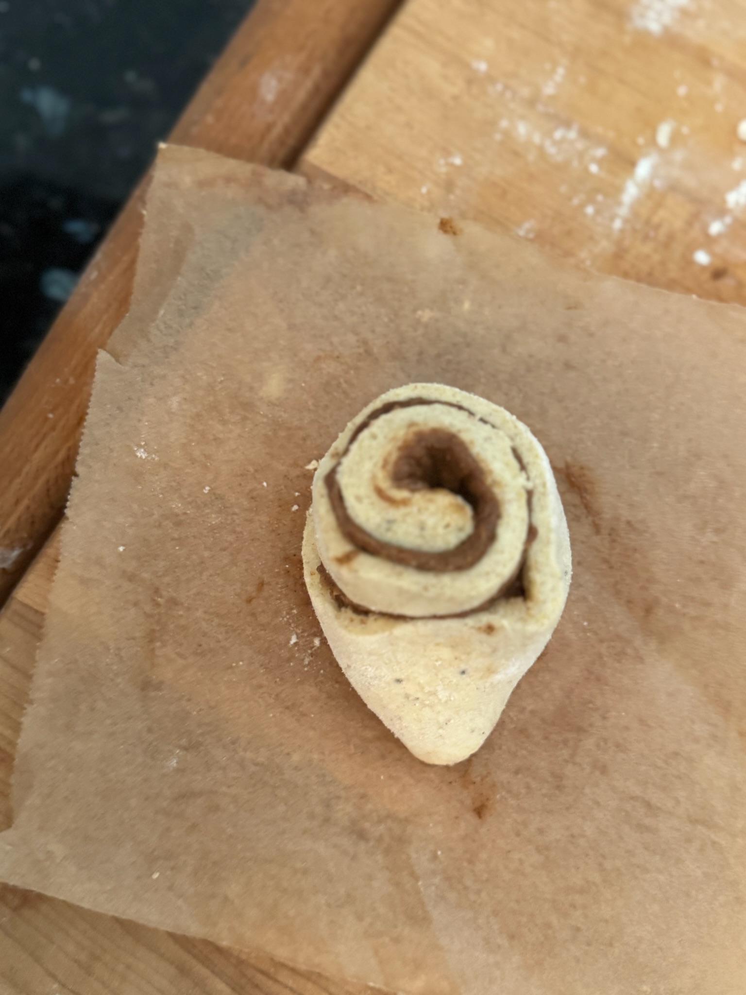Roll of raw gluten free cinnamon roll dough with the tail of raw dough sticking out 
