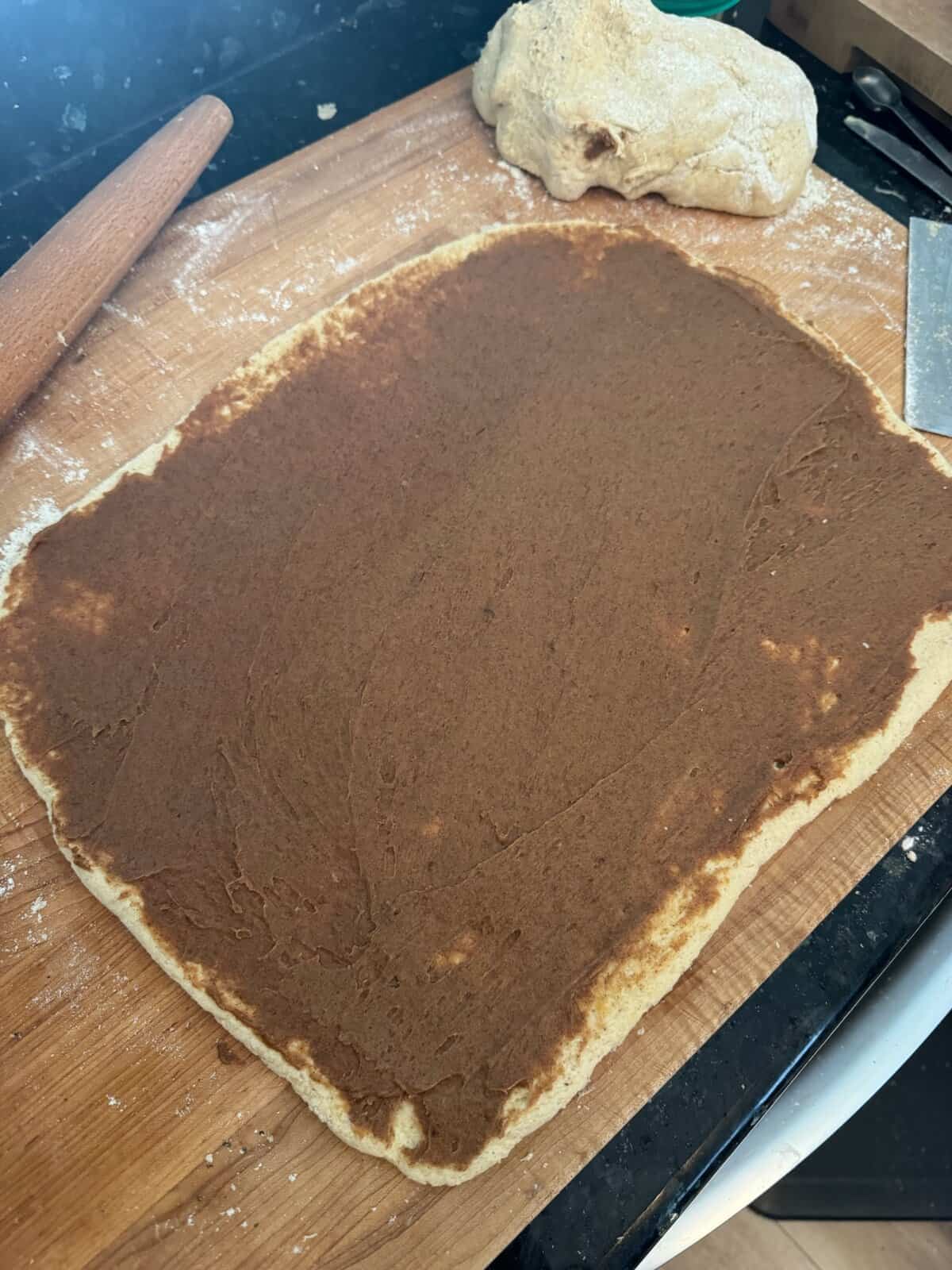 Rectangle of raw dough covered in brown cinnamon sugar paste