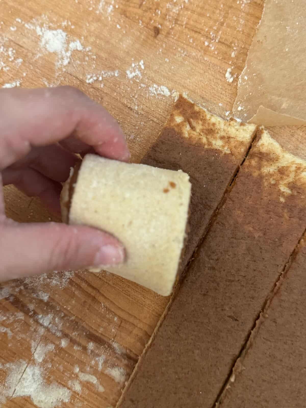 A hand rolling a long strip of gluten free dough with cinnamon filling