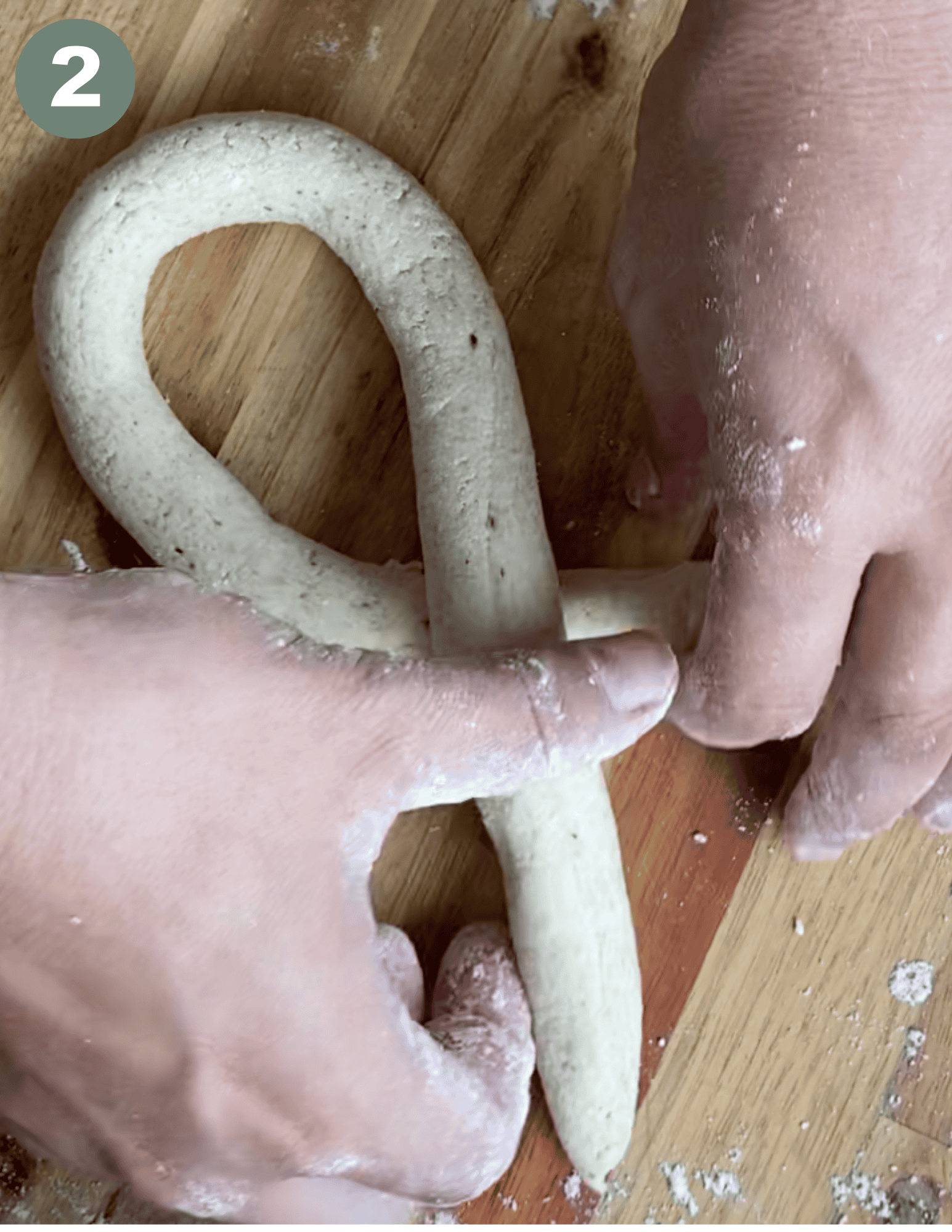 Hands shaping gluten-free pretzel dough into a traditional pretzel form.