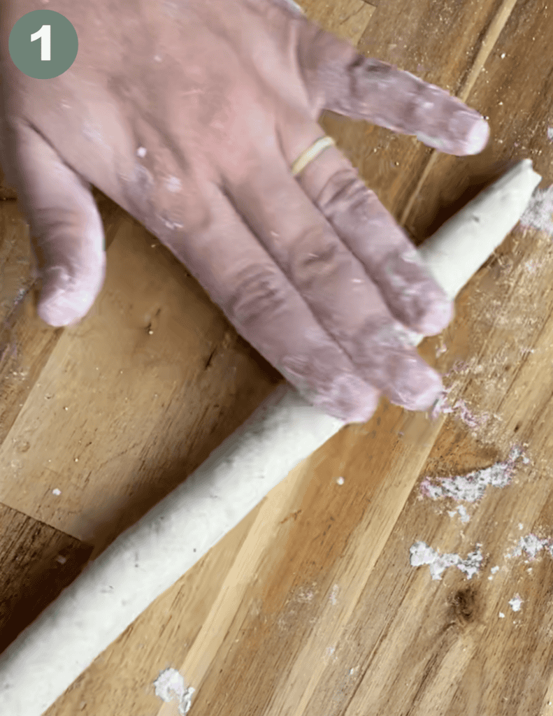 Hand rolling gluten-free pretzel dough on a wooden surface for baking.