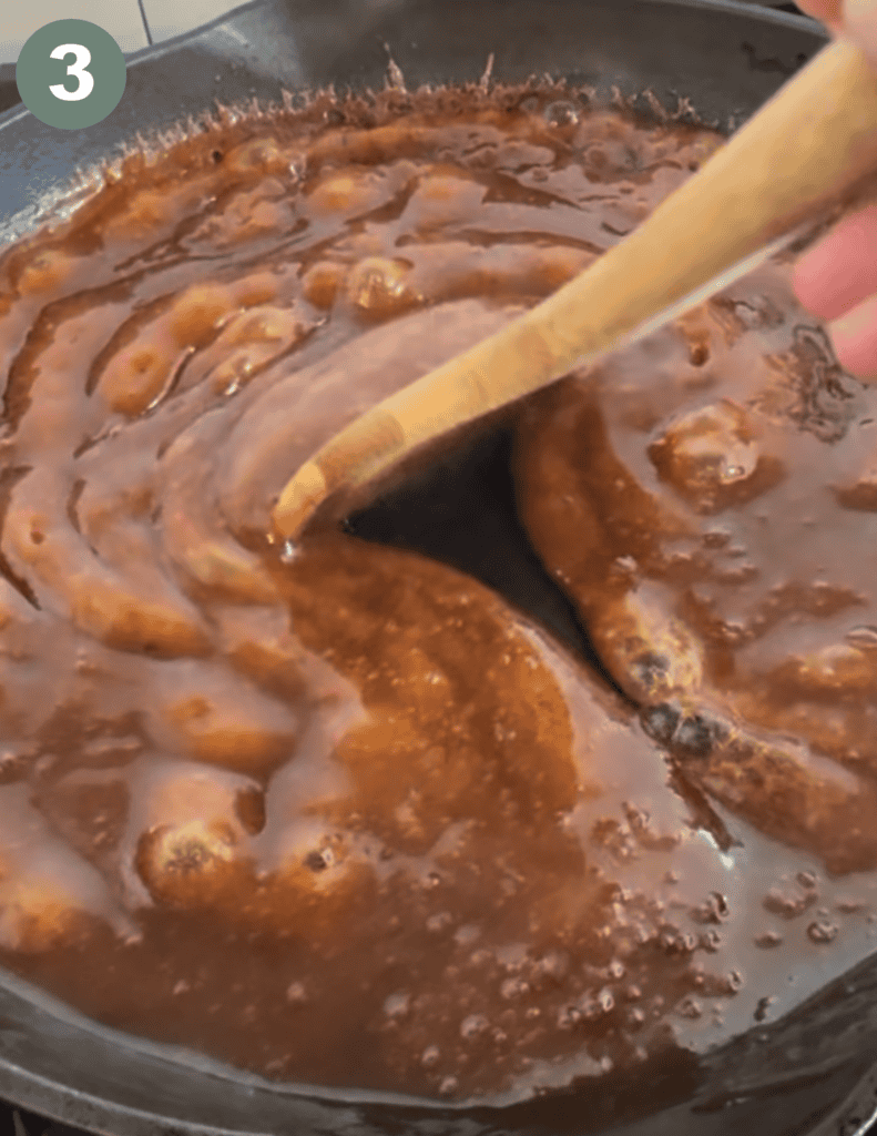 Wooden spoon stirring brown sauce 