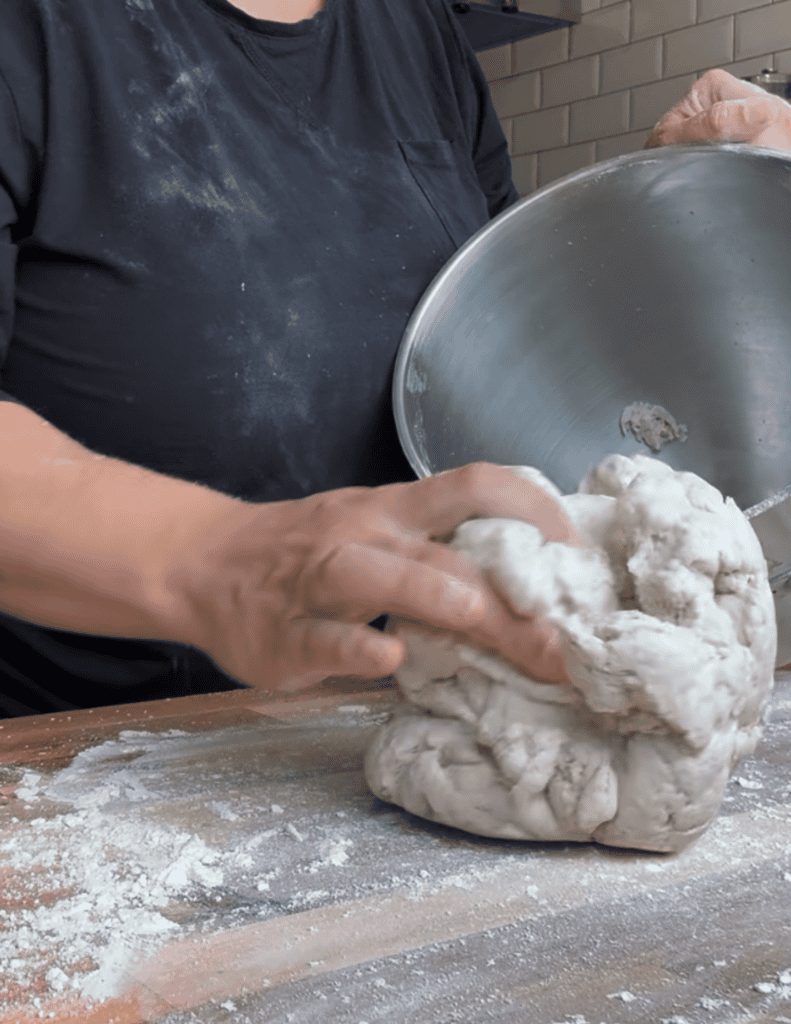 A hand putting a large ball of gluten free pizza dough on the counter
